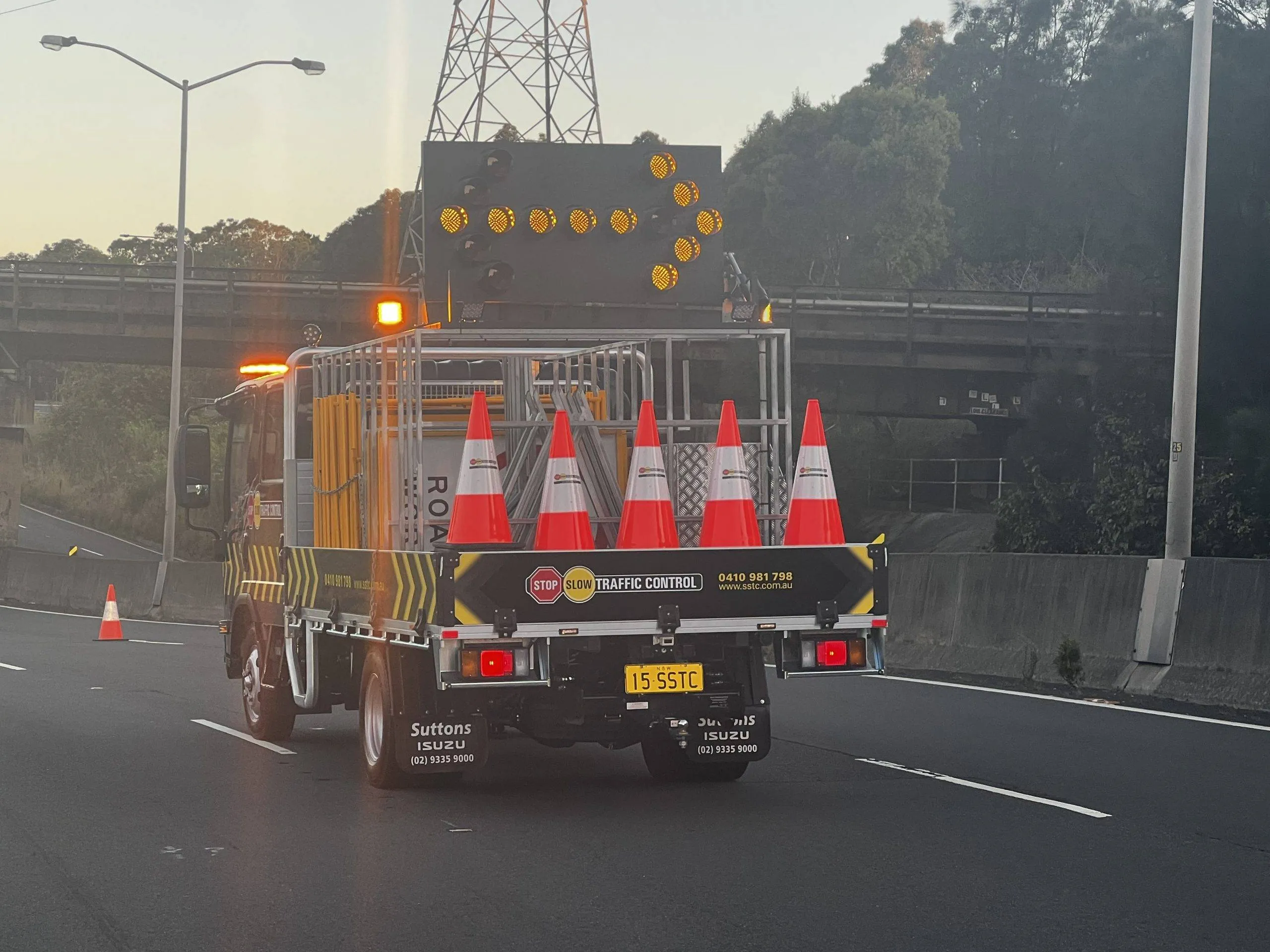 SSTC truck with arrow board and cones closing a lane at dusk