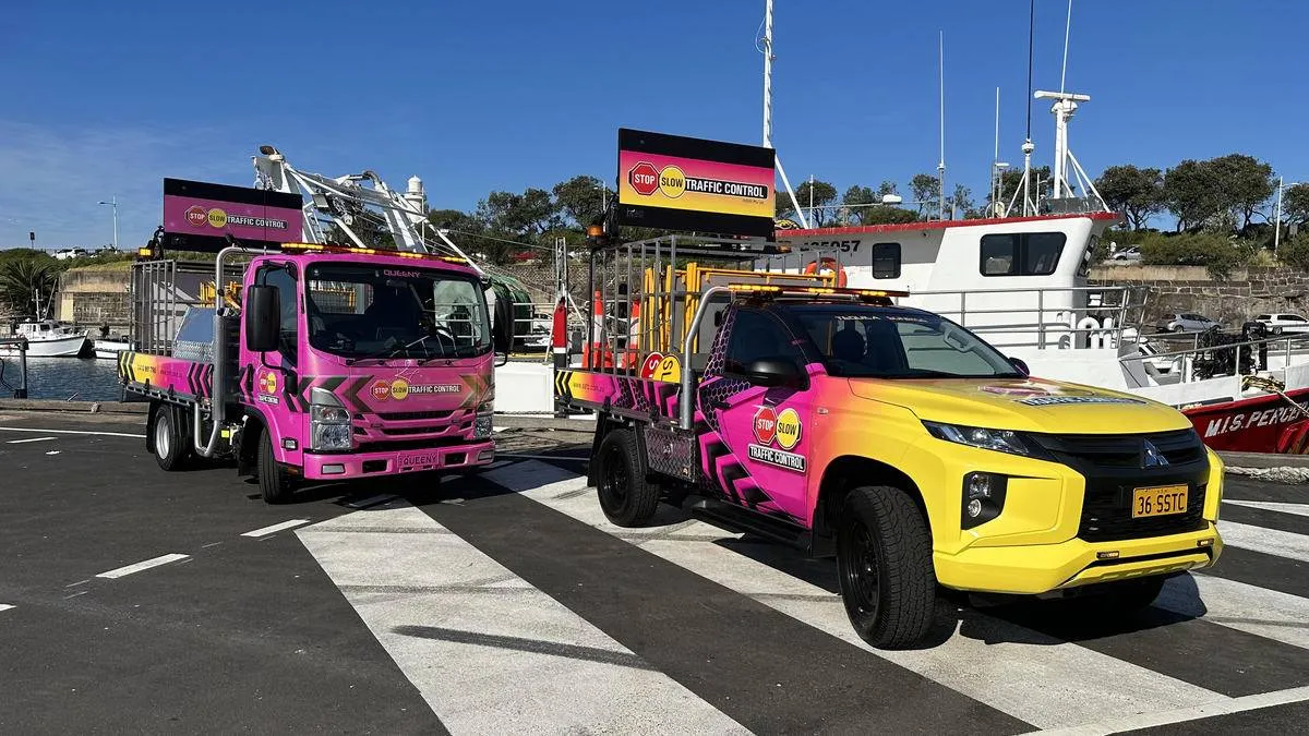 Pink and yellow SSTC trucks parked at a wharf