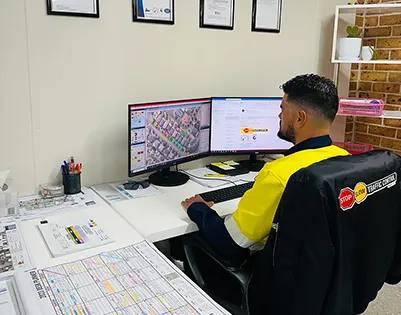 An SSTC planner drawing a traffic plan at a desk with two screens