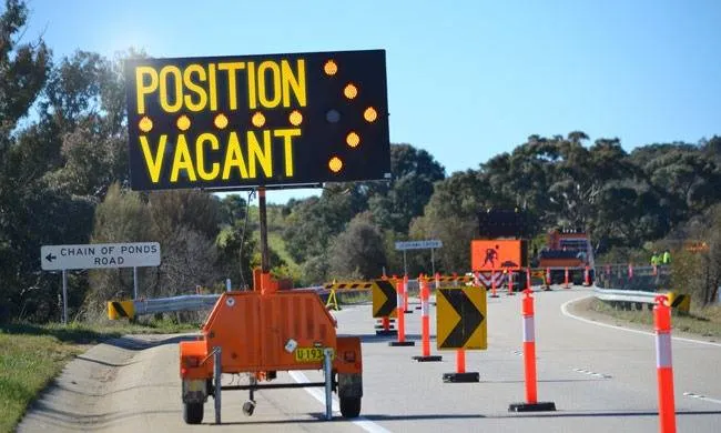 A message board reading POSITION VACANT beside the road